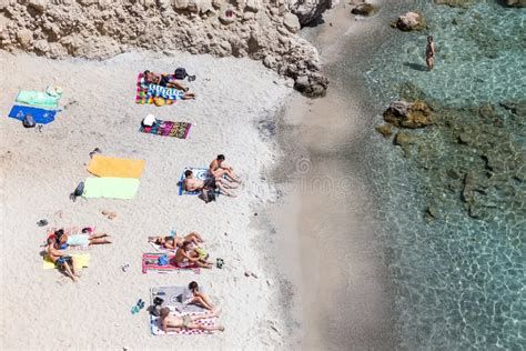 Tourists Sunbathing At The Beach Of Ios Greek Island In Cyclades