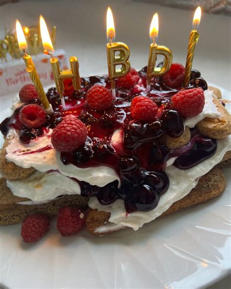 A Birthday Cake With Raspberries And Whipped Cream On It Is Sitting On