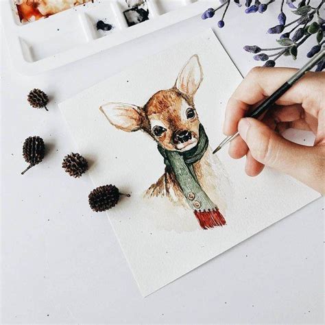 A Person Is Drawing A Deer With Watercolors On Paper Next To Pine Cones