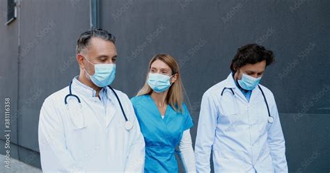 Caucasian Males And Female Doctors Colleagues In Medical Masks Walking