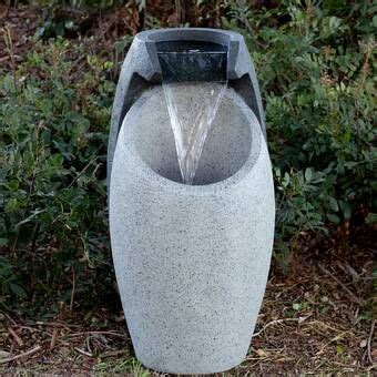 An Outdoor Fountain With Water Coming Out Of It S Sides In Front Of