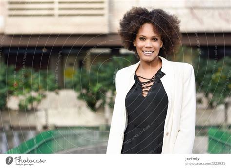 Young Black Woman Afro Hairstyle Sitting On A Wall Smiling A