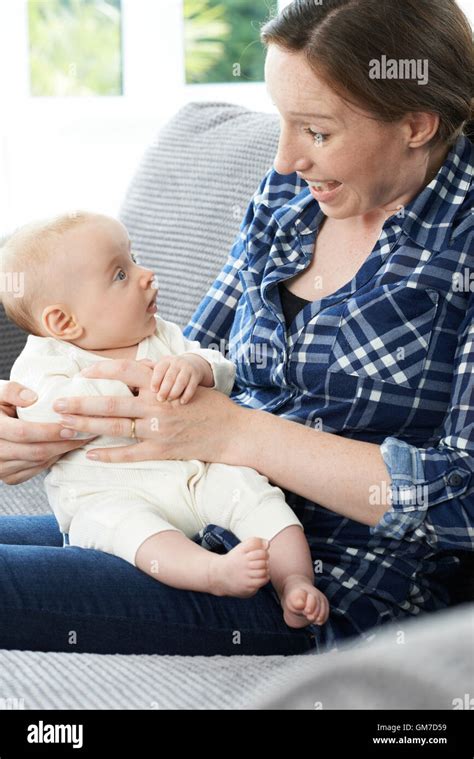 Mother Cuddling Baby Daughter On Sofa Stock Photo Alamy