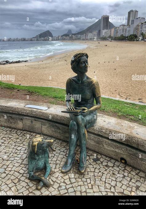 A bronze statue of a lady sitting with her dog at Leme beach promenade ...