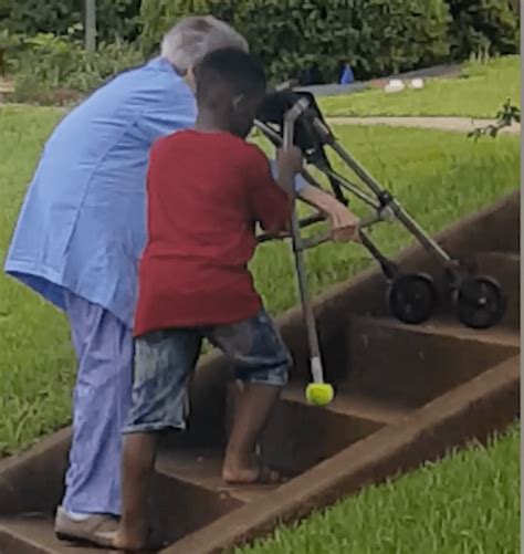 A Thoughtful Young Boy Gets Out of Car to Help an Elderly Woman With a Walker Climb Safely Up Stairs