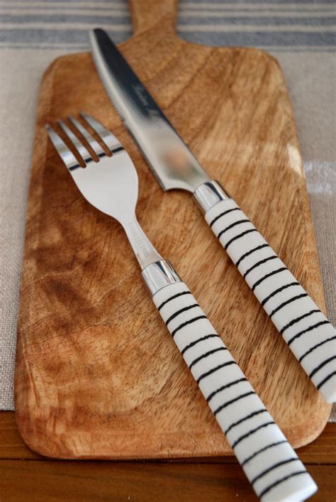 Two Forks And A Knife On A Wooden Cutting Board Next To A Striped Place Mat