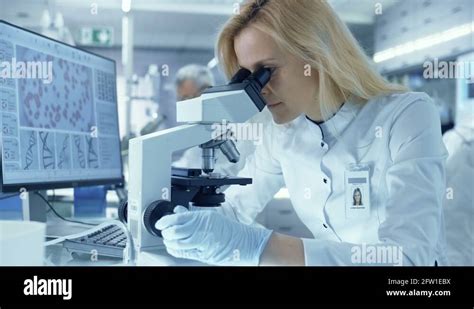 Female Research Scientist Looks At Biological Samples Under Microscope