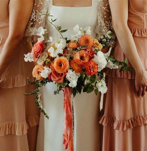 The Bridesmaids Are Holding Their Bouquets With Orange And White