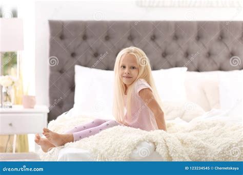 Petite Fille Mignonne S Asseyant Sur Le Lit Avec Des Oreillers Image