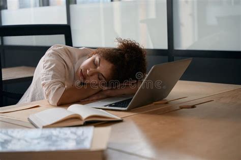 Female Employee Sleeping With Her Head Resting On Her Desk Stock Image