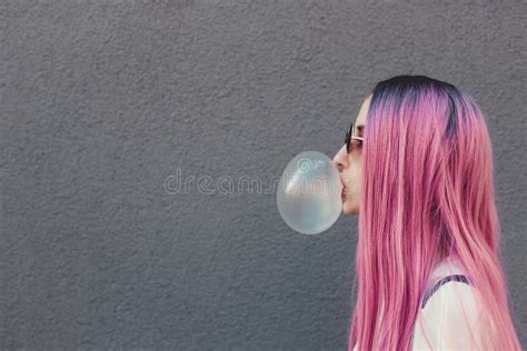 Stylish Young Hipster Woman With Long Pink Hair Blowing A Bubble With