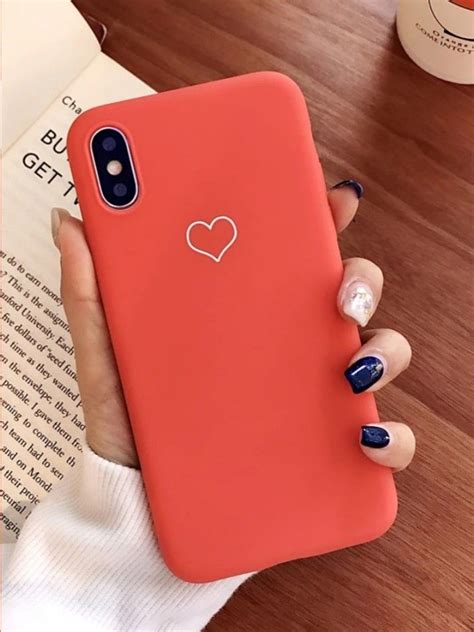 A Woman Holding An Orange Iphone Case With A Heart On The Front And