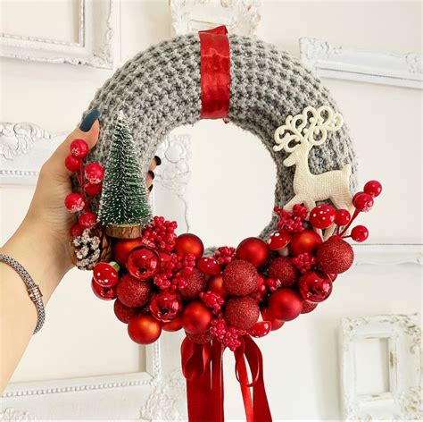 A Person Holding A Christmas Wreath With Ornaments On It