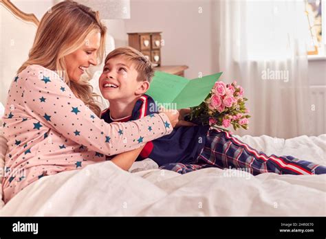 Loving Son Surprising Mother In Bed With Flowers And Homemade Card On