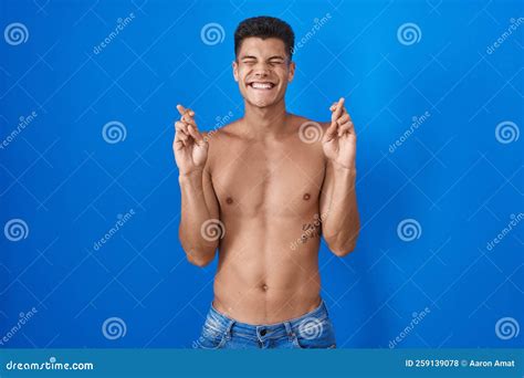 Young Hispanic Man Standing Shirtless Over Blue Background Gesturing