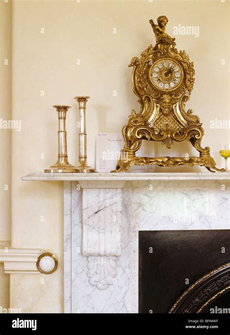 Close Up Of Rococo Gilt Clock And Candlesticks On Marble Mantelpiece