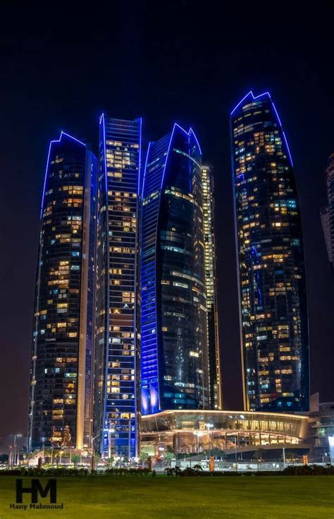 Some Very Tall Buildings Lit Up In The Night Sky With Blue Lights On