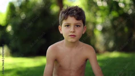 Handsome child in outdoor garden. Shirtless young boy looking to camera