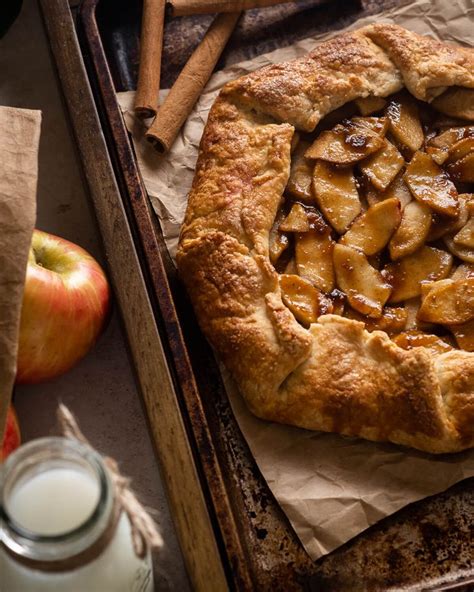 An Apple Pie Sitting On Top Of A Baking Pan Next To Apples And Cinnamon