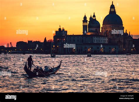 Venice (Italy) - Gondola in a golden sunset of Venice Lagoon with the background Basilica of ...