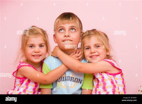 3 Year Old Twin Girls Embracing A Seven Year Old Boy Stock Photo Alamy