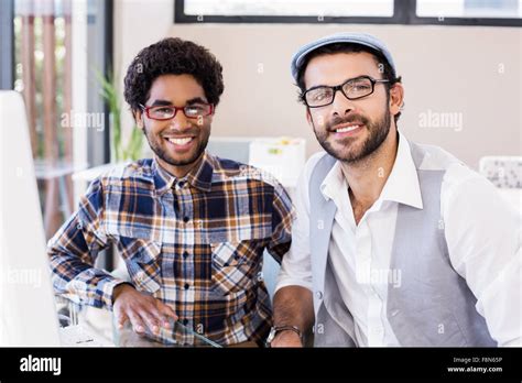 Smiling Gay Couple Sitting At Desk Stock Photo Alamy