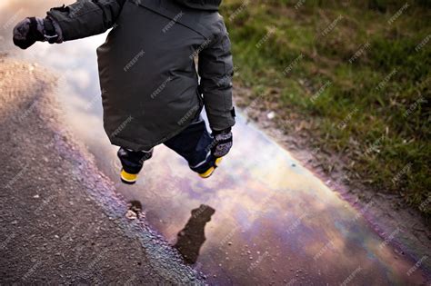 Premium Photo Child Jumps Into A Puddle In Which The Sky Is Reflected