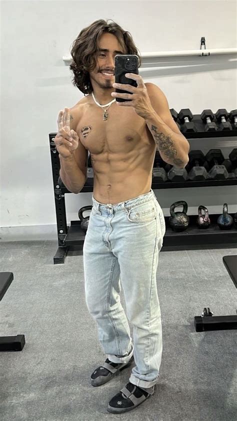 A Shirtless Man Taking A Selfie With His Cell Phone In The Middle Of A Gym