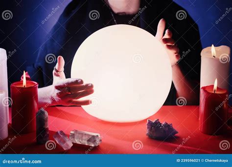 Soothsayer Using Glowing Crystal Ball To Predict Future At Table In