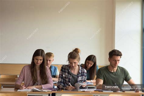 Students studying at desk in classroom — post secondary education, wall ...