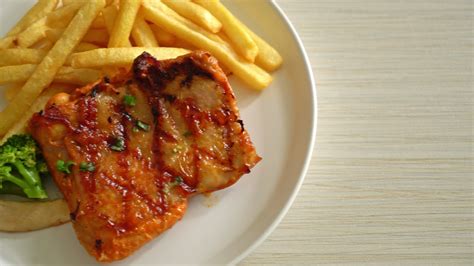 grilled chicken steak with potato chips or french fries on white plate ...