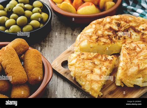 Traditional spanish tapas. Croquettes, olives, omelette, ham and patatas bravas on wooden table ...