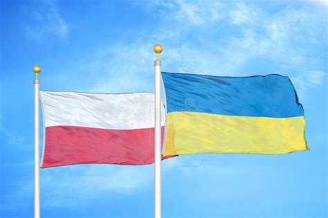 Poland And Ukraine Two Flags On Flagpoles And Blue Cloudy Sky Stock