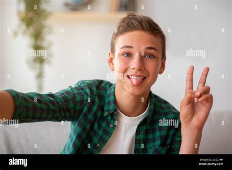 Cute teen boy taking selfie, showing tongue and peace gesture Stock ...