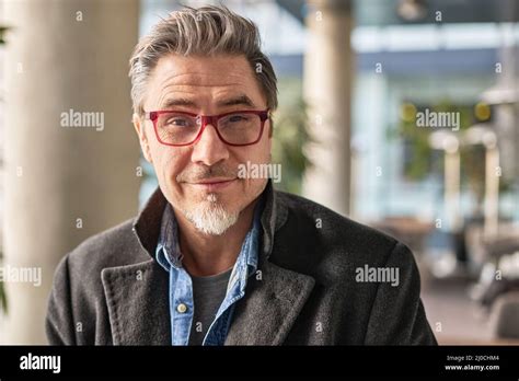 Portrait Of Happy Middle Aged Man In Glasses Standing In Office Lobby