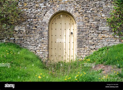 Arched Wooden Garden Door And Cotswold Stone Wall In Front Of A House