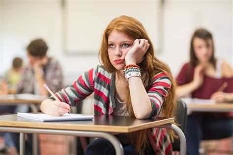 Bored Female Student With Others Writing Notes In Classroom Stock Photo