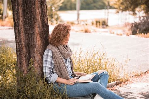 Jolie Femme Assise Sur Lherbe Et Livre De Lecture Photo Gratuite