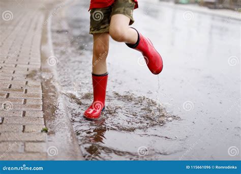 Child Wearing Red Rain Boots Jumping Into A Puddle Stock Photo Image