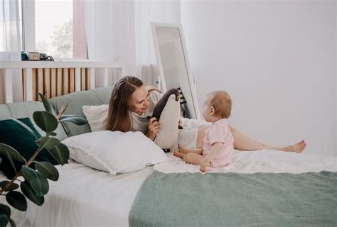 Una hermosa madre y su hija están sentadas en la cama y juegan con un