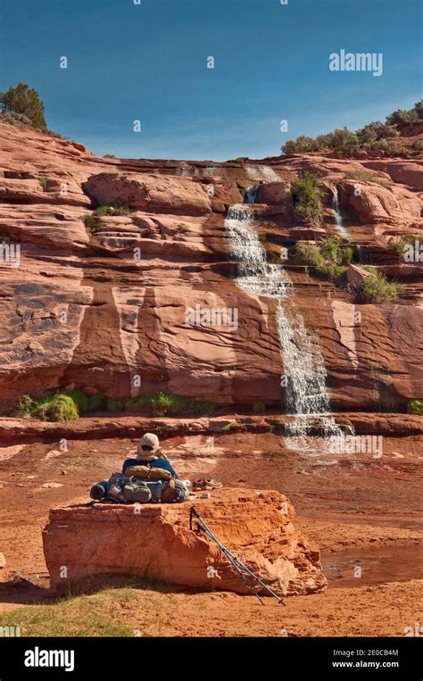 Hiker Resting At Waterfall Keet Seel Canyon In Skeleton Mesa On Trail