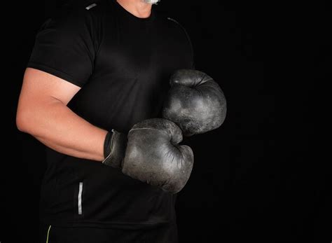 Premium Photo Midsection Of Man Holding Hat Against Black Background