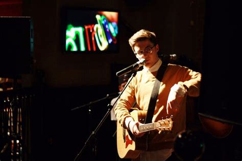 a man standing in front of a microphone while holding a guitar