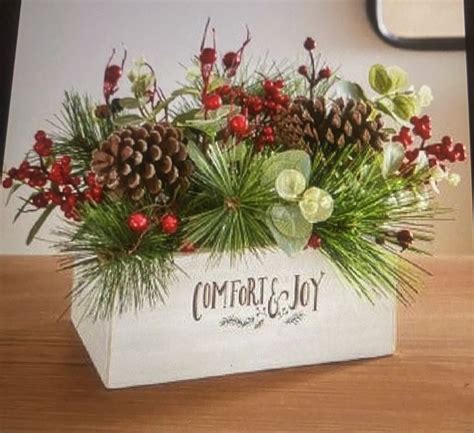 A Wooden Box Filled With Pine Cones And Evergreens Sitting On Top Of A