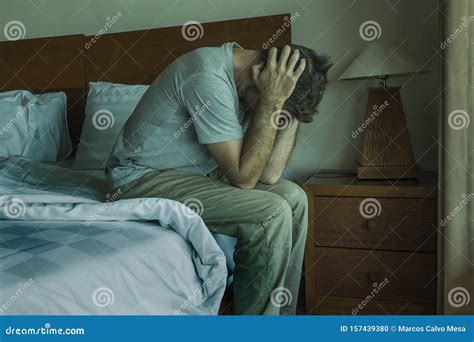 Dramatic Lifestyle Portrait Of Man Sitting Depressed On Bed Crying