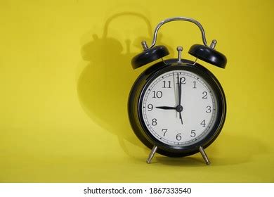 Black Alarm Clock On Yellow Background Stock Photo