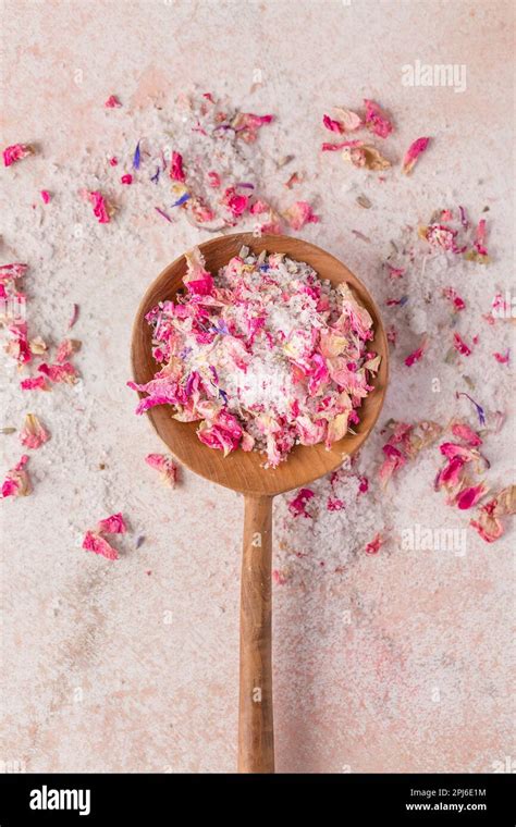 See Salt Wih With Dried Flower Petals In Wooden Scoop On Pink Marble