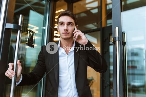 Serious Business Man In Suit Talking On Phone In Office And Holding The