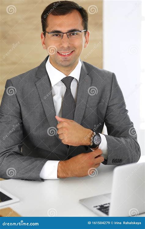 Cheerful Smiling Businessman Sitting At A Desk In Modern Office