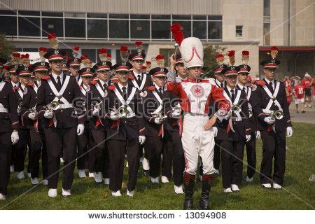 a marching band in front of a building with people dressed in black and ...